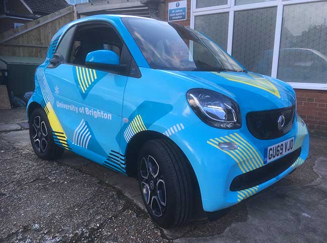 Smart Car with vinyl graphics advertising the University of Brighton, Brighton