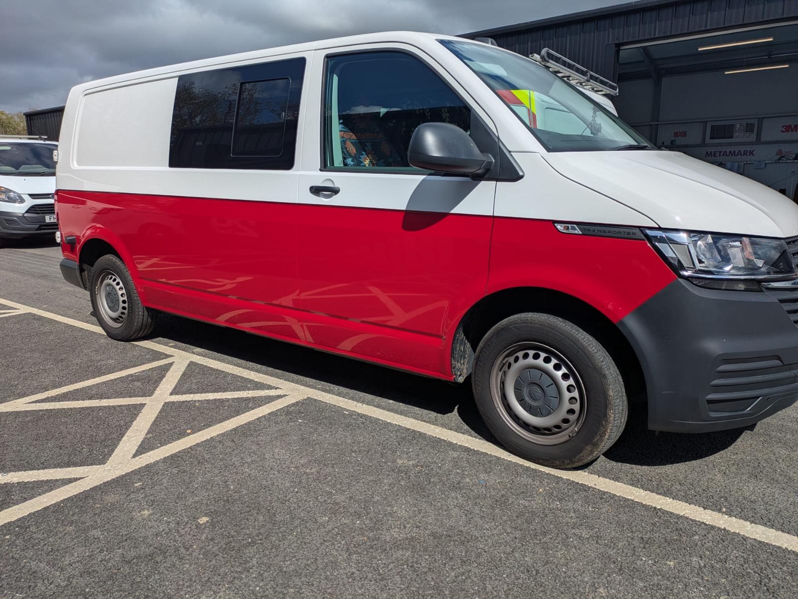 White VW Transporter van with a glossy red vinyl half wrap applied to the lower bodywork by Sussex Van Wraps